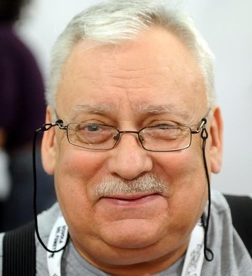 Ilustracja przedstawiająca Geralta z Rivii w akcji, otoczonego elementami ze świata Wiedźmina, takimi jak potwory i magiczne znaki.