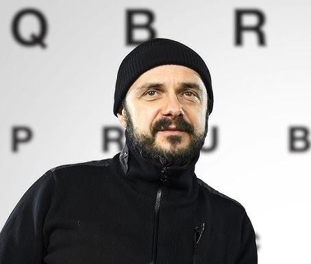 Arkadiusz Jakubik, wokalista zespołu Dr Misio, podczas energicznego występu na scenie, trzymający mikrofon.
