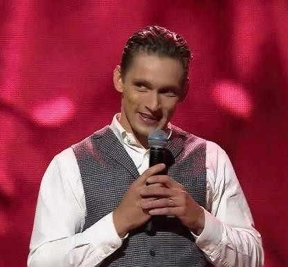 Filip Gurłacz w trakcie występu, z intensywnym wyrazem twarzy, na tle sugerującym plan filmowy lub telewizyjny, podkreślający jego aktorski talent.