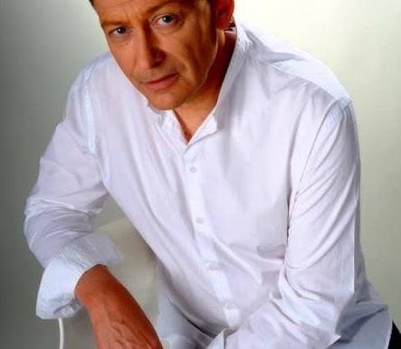 Jacek Borkowski na scenie lub w studiu nagraniowym, symbolizujący jego wszechstronną karierę aktorską, wokalną i dubbingową.