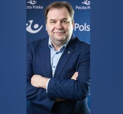 Sebastian Mikosz w garniturze, z pewnym wyrazem twarzy, na tle symbolizującym jego karierę w lotnictwie i Poczcie Polskiej.