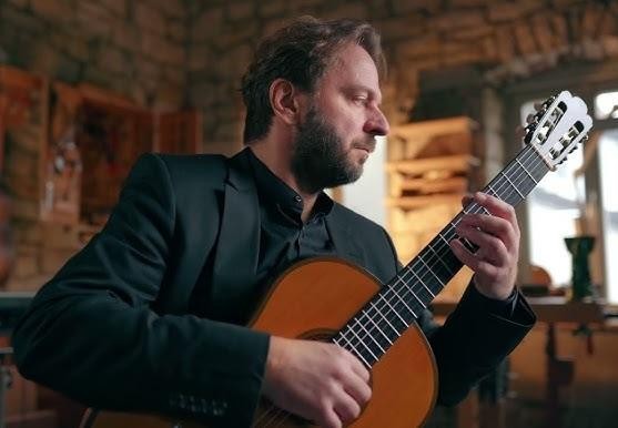 Marcin Dylla, gitarzysta klasyczny, skupiony na grze na gitarze podczas koncertu.