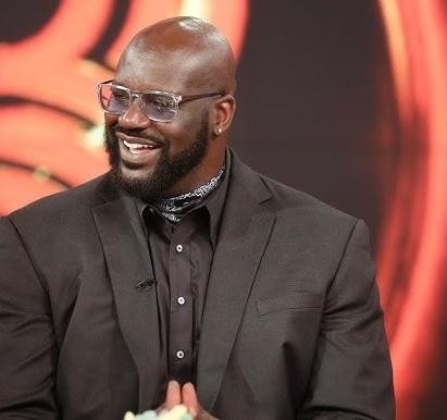 Shaquille O'Neal w koszulce Lakersów, wykonujący potężny wsad do kosza podczas meczu.