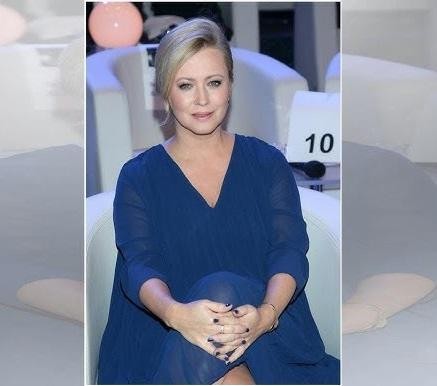 Agnieszka Wagner w swobodnej pozie, uśmiechnięta, na tle sugerującym aktywności związane z podróżami lub sportem, z dyskretnie widocznymi tatuażami.