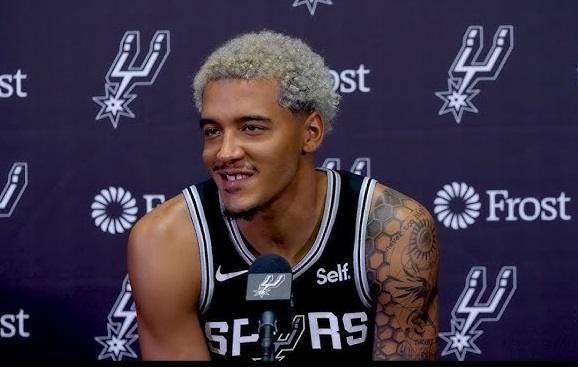 Jeremy Sochan w koszulce San Antonio Spurs, w trakcie dynamicznej akcji z piłką na boisku.