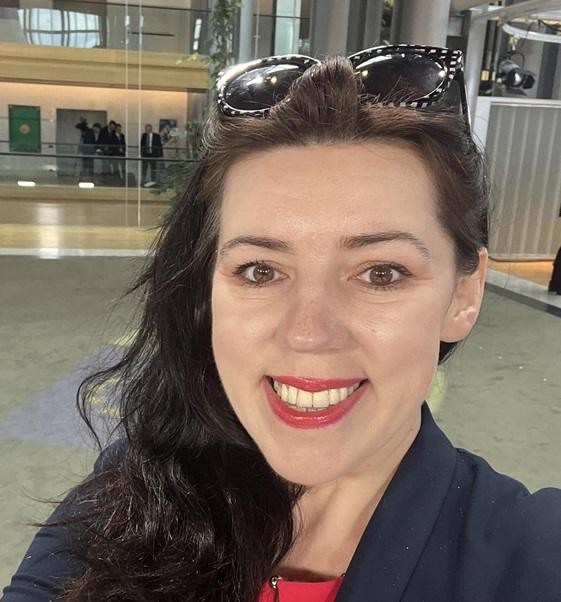 Dominika Ćosić przemawiająca na konferencji lub podczas debaty, ukazująca jej zaangażowanie w tematykę polityki międzynarodowej i Unii Europejskiej.