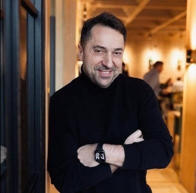 Marcin Miller przeglądający media społecznościowe, z uśmiechem na twarzy, w domowym otoczeniu.
