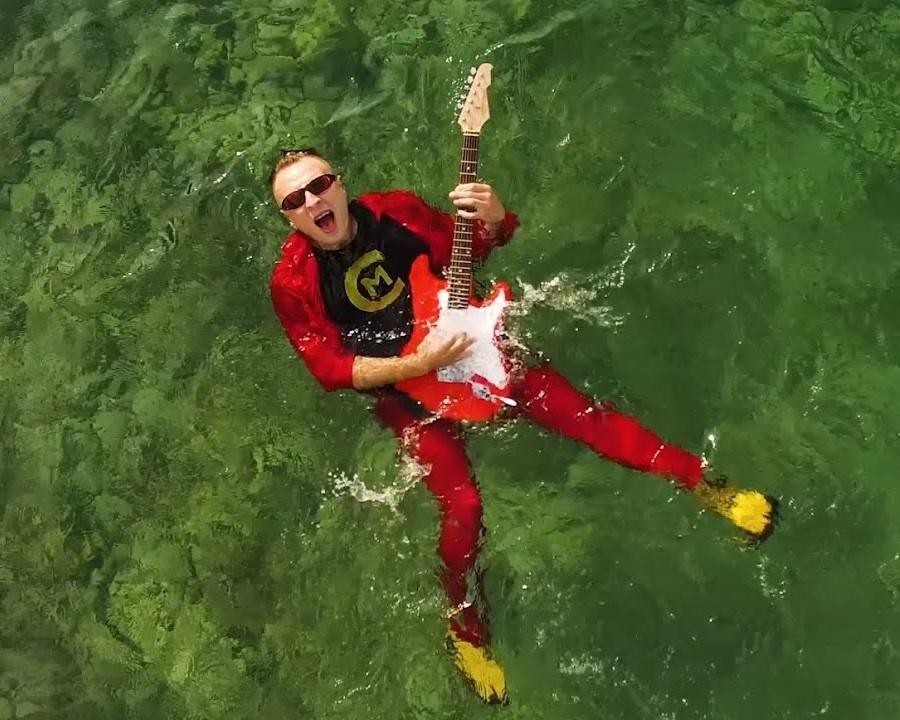 Czadoman podczas dynamicznego występu na scenie, z mikrofonem w ręku, w tle barwne światła koncertowe.